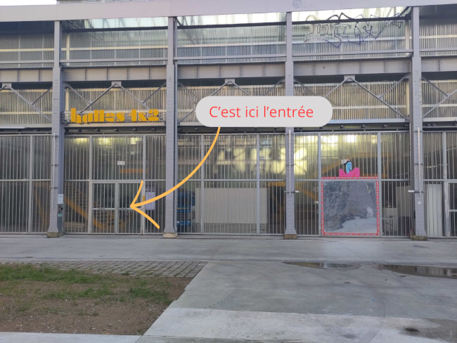 Entrée de la halle 1 et 2 : bâtiment de type hangar avec écrit en jaune sur le fronton 'Halles 1 & 2' 